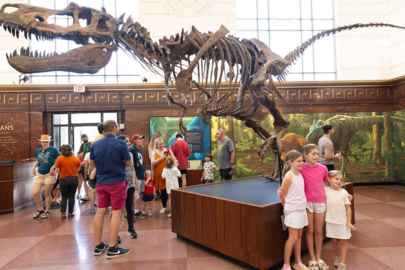 Children posing in front of a dinosaur statue at the Texas Science & Natural History Museum.