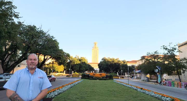 Member of UT Irrigation crew in front of lawn and UT tower